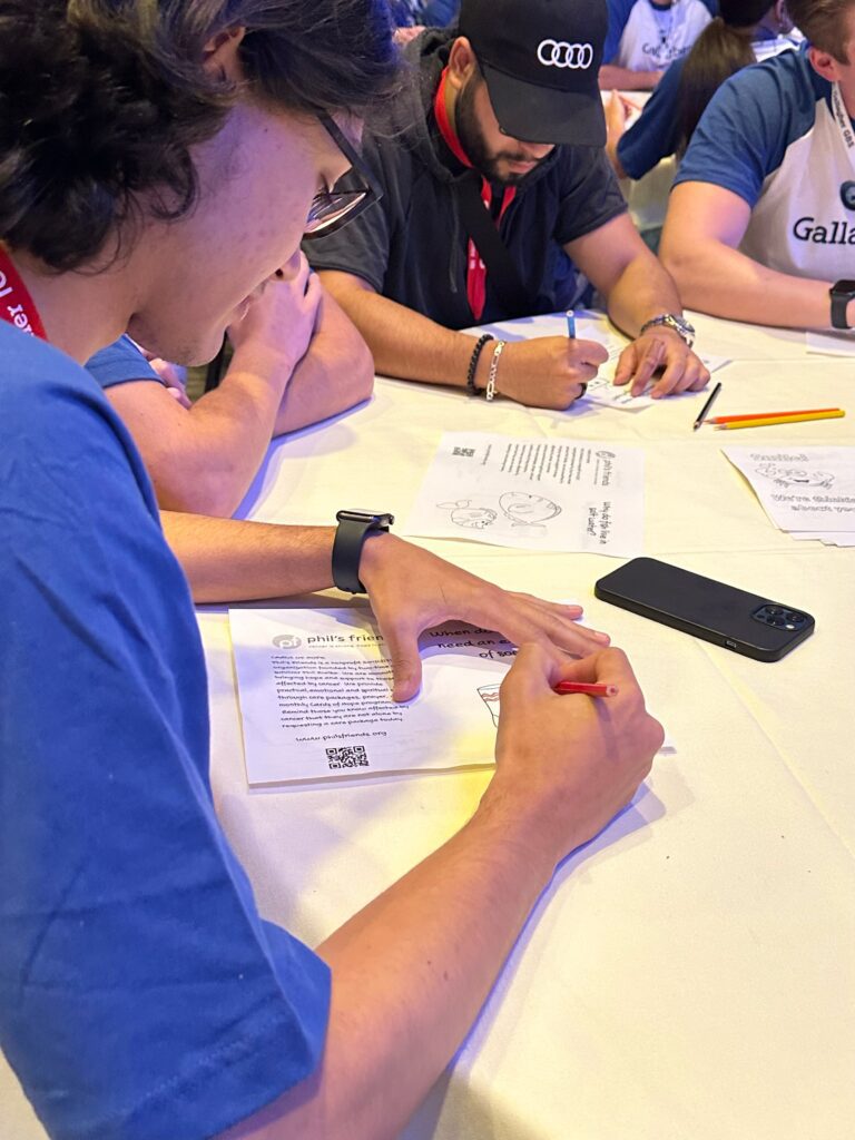 People sitting at a table are writing on worksheets with pens and pencils. A smartphone and other writing materials are also on the table, as they discuss Chicago faith-based cancer support resources.