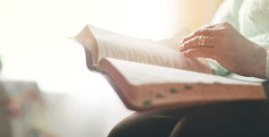 An elderly person reading an open book.